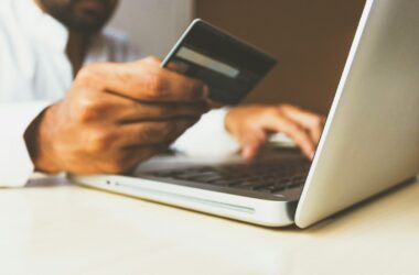 person using laptop computer holding card
